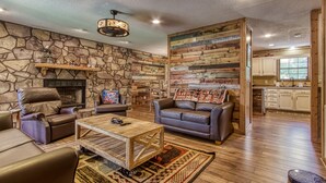 A cozy living room with a stone fireplace, leather sofas, and a wooden coffee table. - Stoneybrook Valley Ranch 2,  3Bed/2Bath, DOG Friendly, 1.5 Acres Great Mtn views (Sevierville)