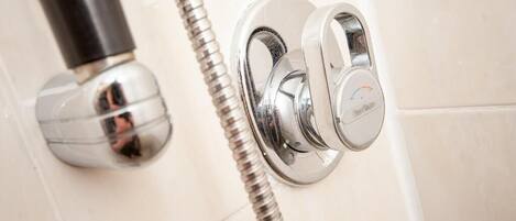 A chrome shower knob and a flexible hose attached to a wall-mounted faucet.
