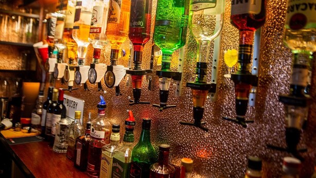 Um bar com diversas garrafas de bebidas e copos nas prateleiras.