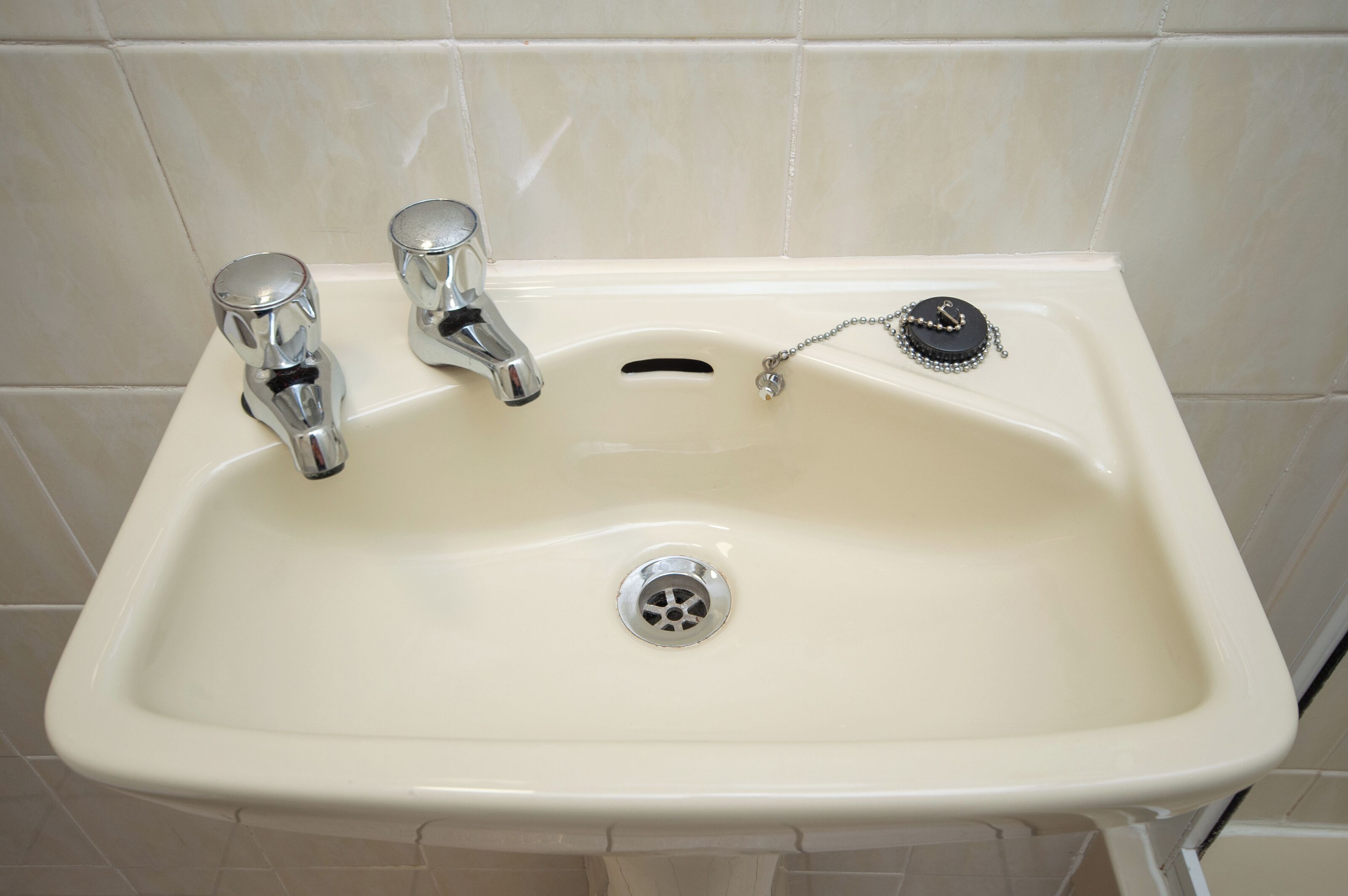 A bathroom sink with two faucets and a drain.