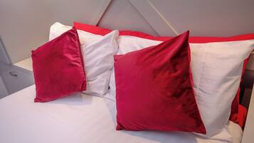 A bed with white and red bedding, including pillows and a red accent pillow.