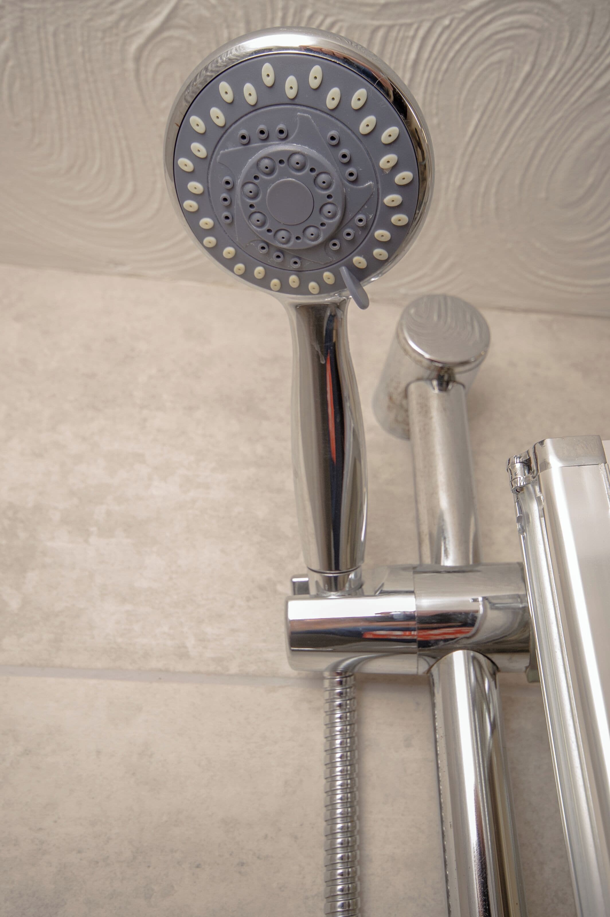 A chrome showerhead with multiple spray nozzles and a handheld shower attachment.