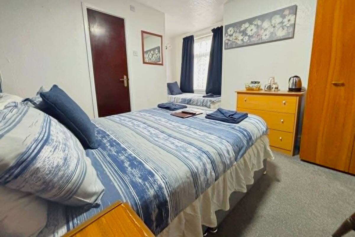 A bedroom with a bed, a dresser, a door, and a painting on the wall.
