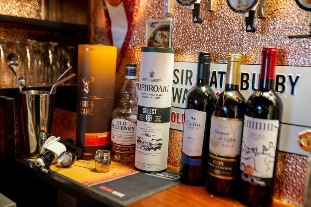 A bar area with various bottles of alcohol, a candle, and a sign that reads 'SIR AT BUBY'.
