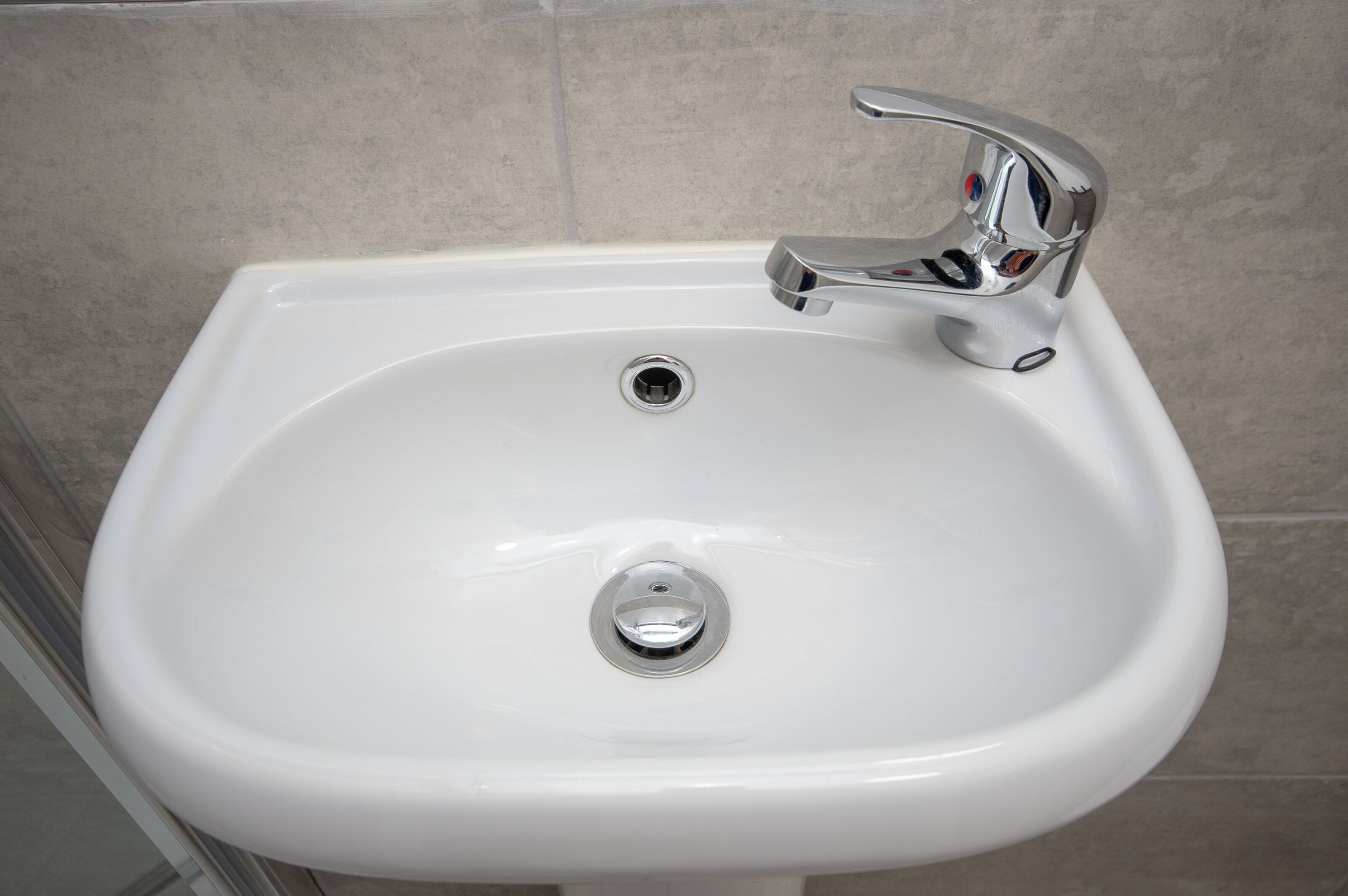 Un lavabo de salle de bain blanc, doté d’un robinet chromé et d’un drain.