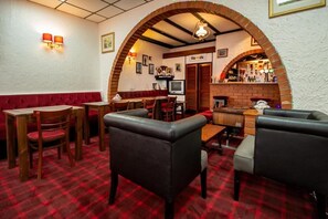 A restaurant interior with a red and white checkered floor, wooden tables and chairs, a brick archway, and a bar area. - Ferndale Hotel (Blackpool)