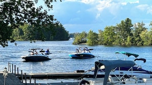 A dock with several boats, including a blue speedboat and a white motorboat, anchored near a wooden pier. - Christie's Mill Inn & Spa, BW Premier Collection (Georgian Bay)