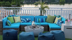 A blue outdoor seating area with cushions, a fire pit, and a view of a lake. - Christie's Mill Inn & Spa, BW Premier Collection (Georgian Bay)