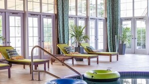 Ein Poolbereich mit Liegestühlen, einem Pool und großen Fenstern.