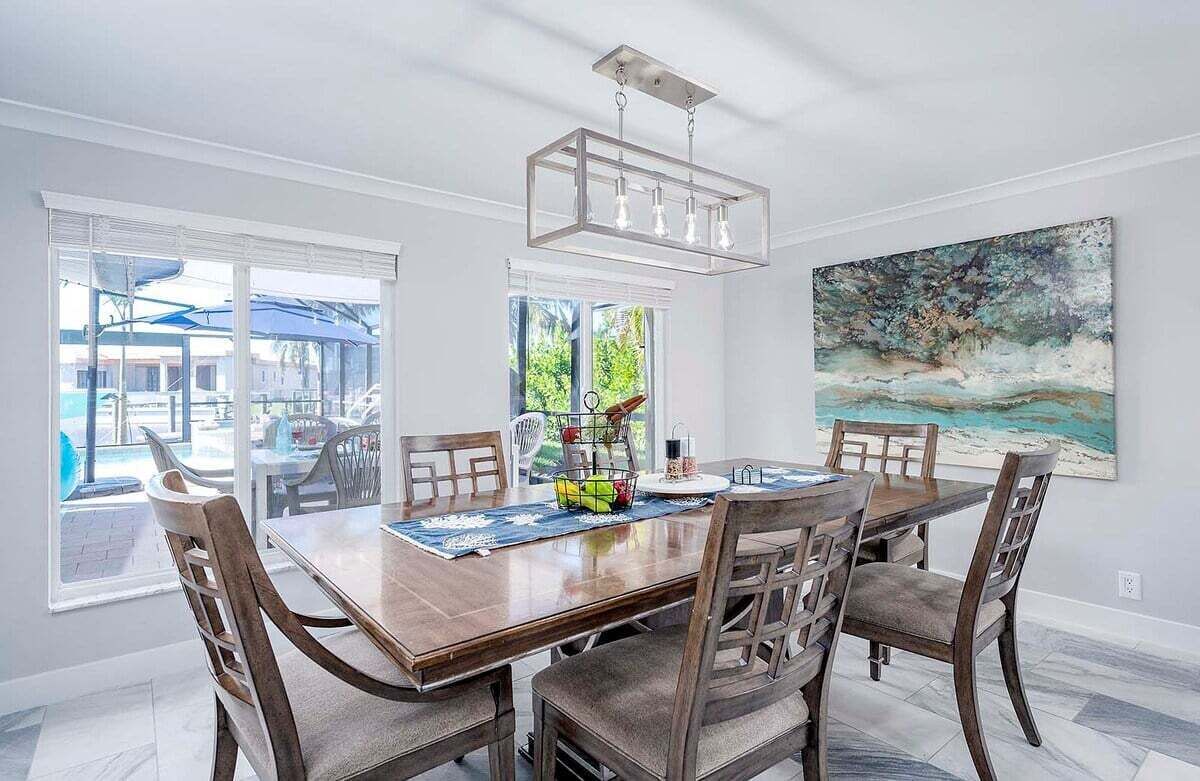 Un coin repas avec une table et des chaises en bois, un luminaire suspendu et un tableau au mur.