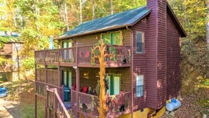 Eine zweistöckige Holzhütte mit Balkon, umgeben von Bäumen.