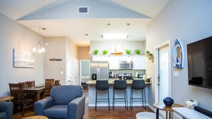 Una sala de estar moderna con comedor, cocina y televisor montado en la pared.