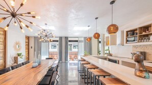 A modern kitchen with a long counter, bar stools, and pendant lighting. - 5-Bed Deluxe Condo • Private Villa Feel • Full Hotel Amenities (Tulum)