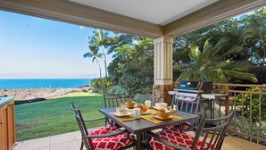 A patio with a table set for dining, overlooking a beach.