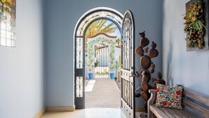 A hallway with a decorative metal gate, a bench with a floral cushion, and a wall-mounted decoration.