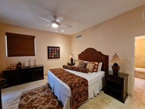 A bedroom with a bed, nightstands, a ceiling fan, a rug, and a wall-mounted picture.