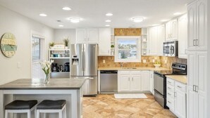 Una cocina moderna con armarios blancos, electrodomésticos de acero inoxidable y una isla grande con taburetes.