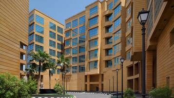 A modern multi-story building with a symmetrical facade, large windows, and a central courtyard with palm trees and a fountain.