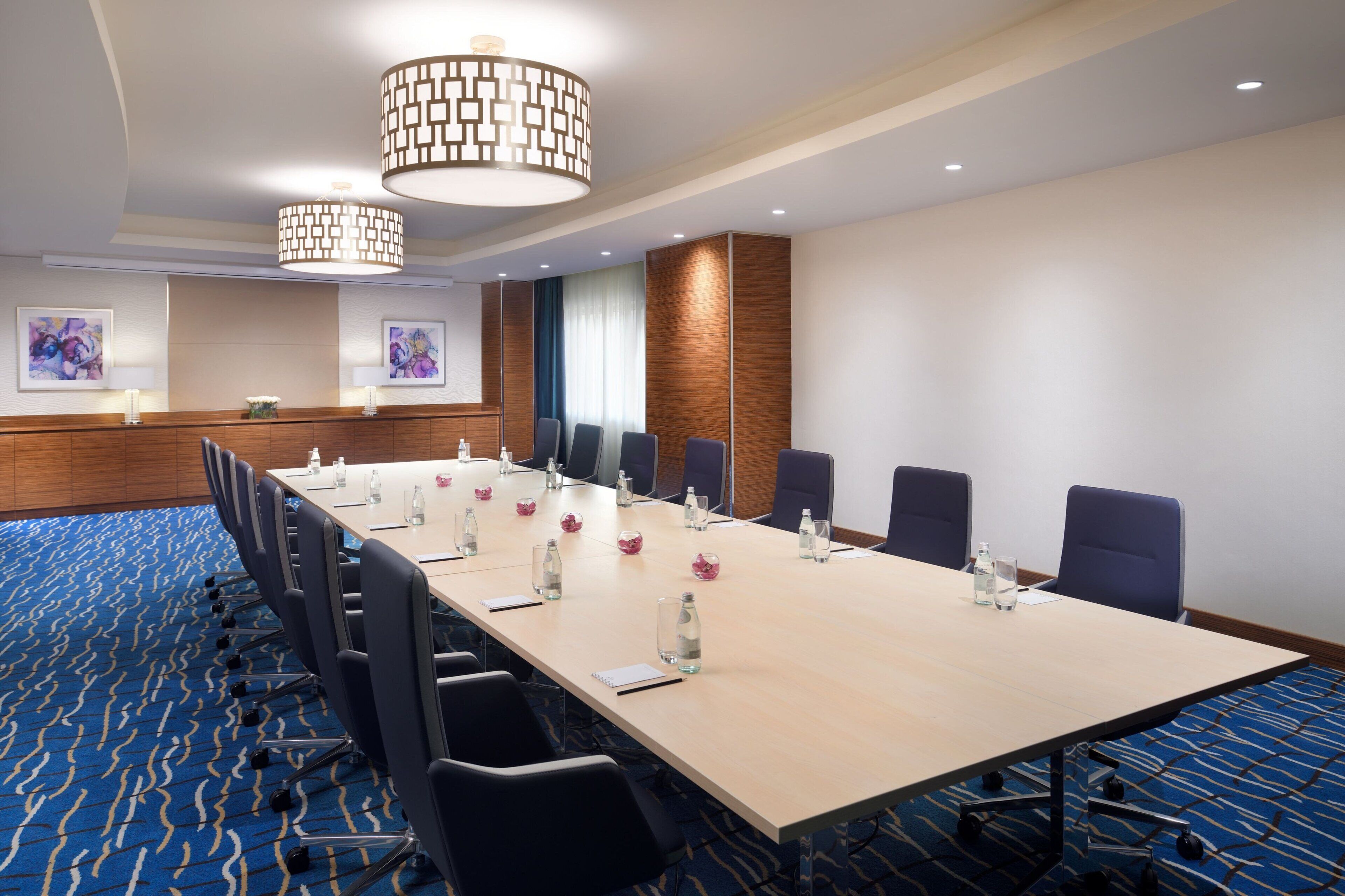 Une salle de conférence avec une longue table, des chaises et un tapis à motifs.