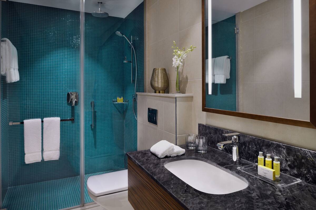 A modern bathroom with a glass-enclosed shower, a white sink, and a large mirror.