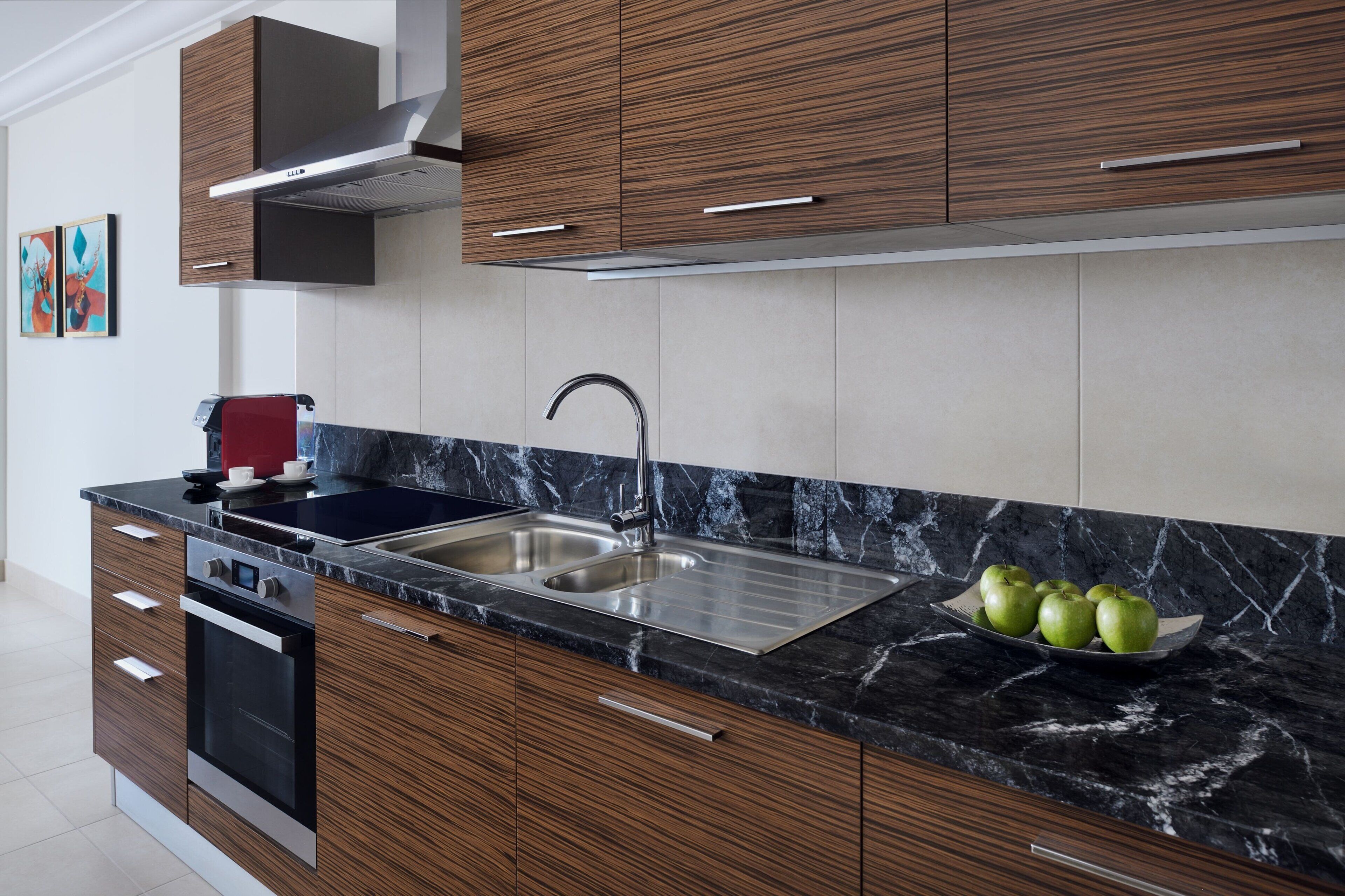 Una cocina moderna con armarios de madera, un lavamanos de acero inoxidable y una encimera de mármol.