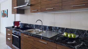 Una cocina moderna con armarios de madera, un lavamanos de acero inoxidable y una encimera de mármol.
