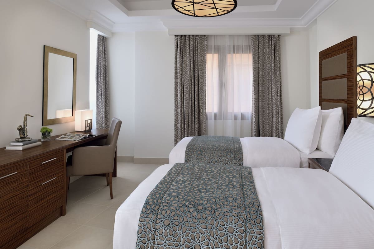 A hotel room with a bed, a desk, a chair, and a large mirror.