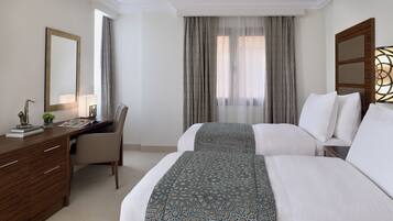 Quarto de hotel com uma cama, escrivaninha, cadeira e um espelho grande.