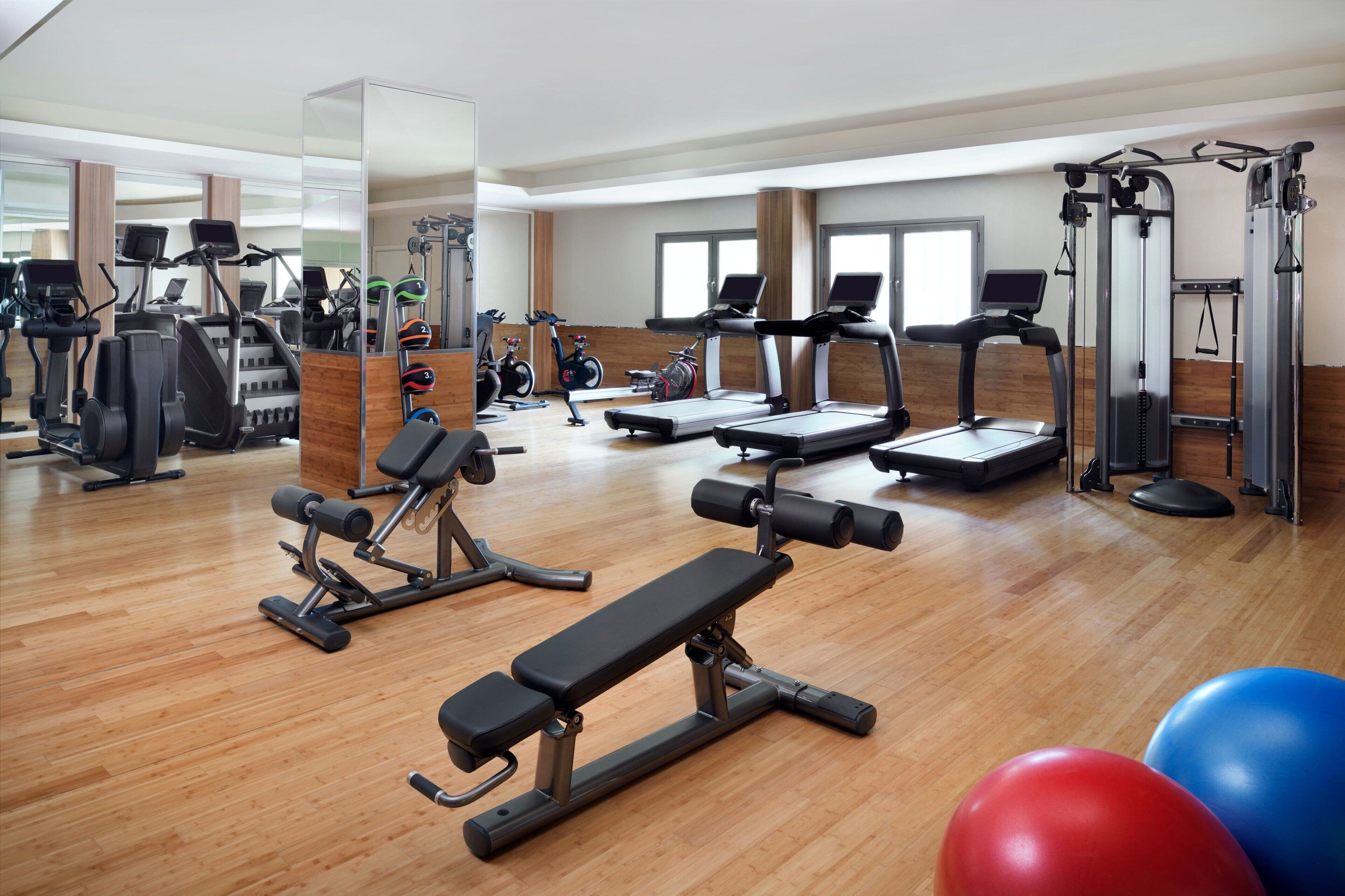 Un gimnasio con cintas de correr, elípticas y equipo de pesas.