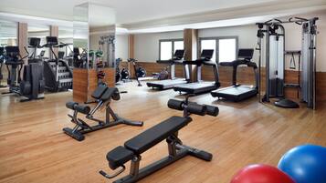 Un gimnasio con cintas de correr, elípticas y equipo de pesas.
