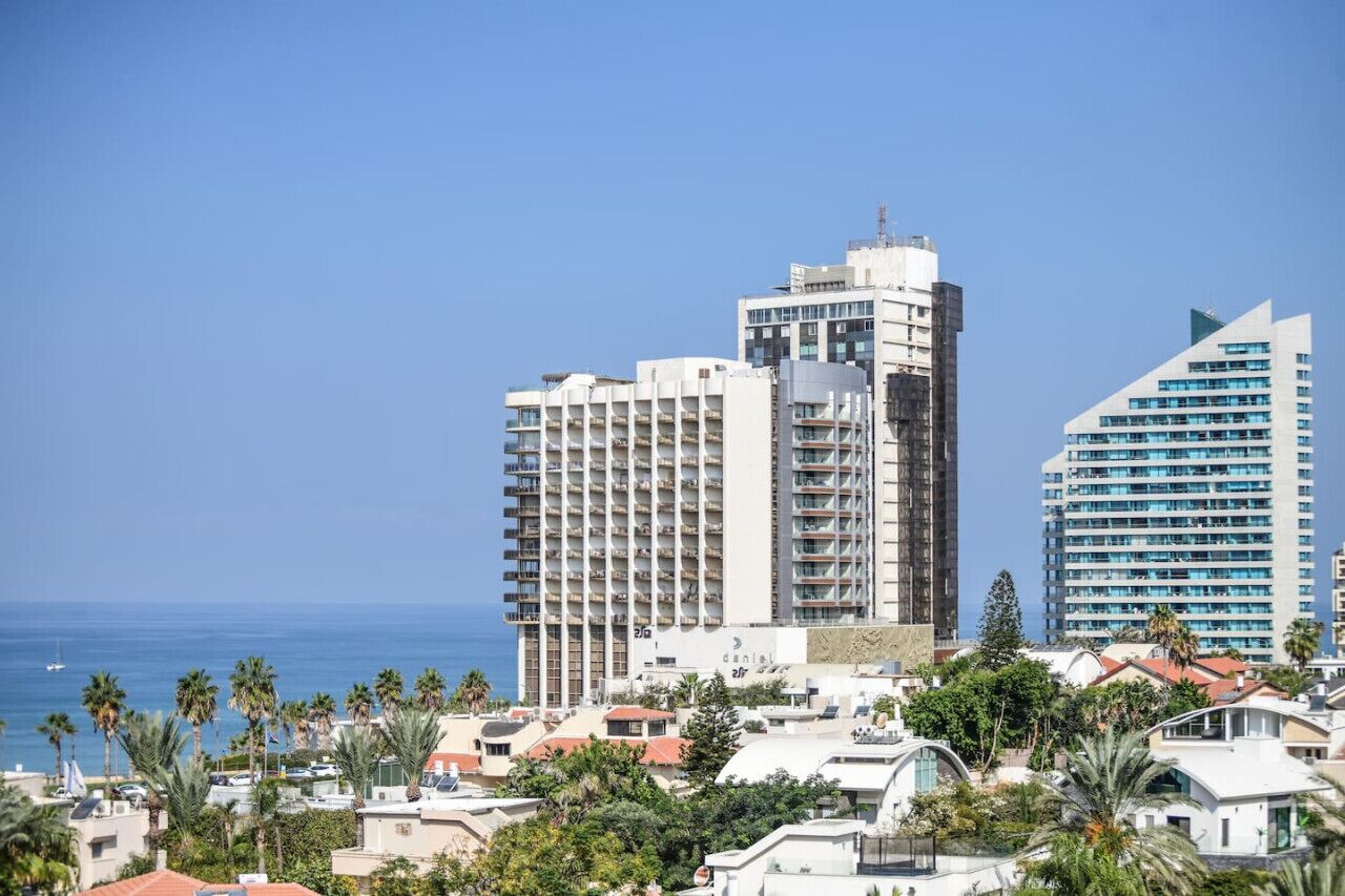 Un paisaje urbano costero con modernos rascacielos, incluyendo un hotel destacado con balcones y vistas al mar.