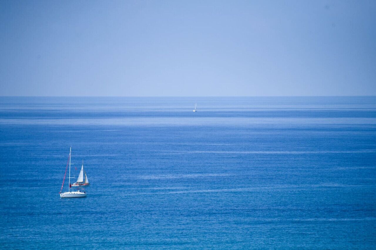 A calm sea with two sailboats.