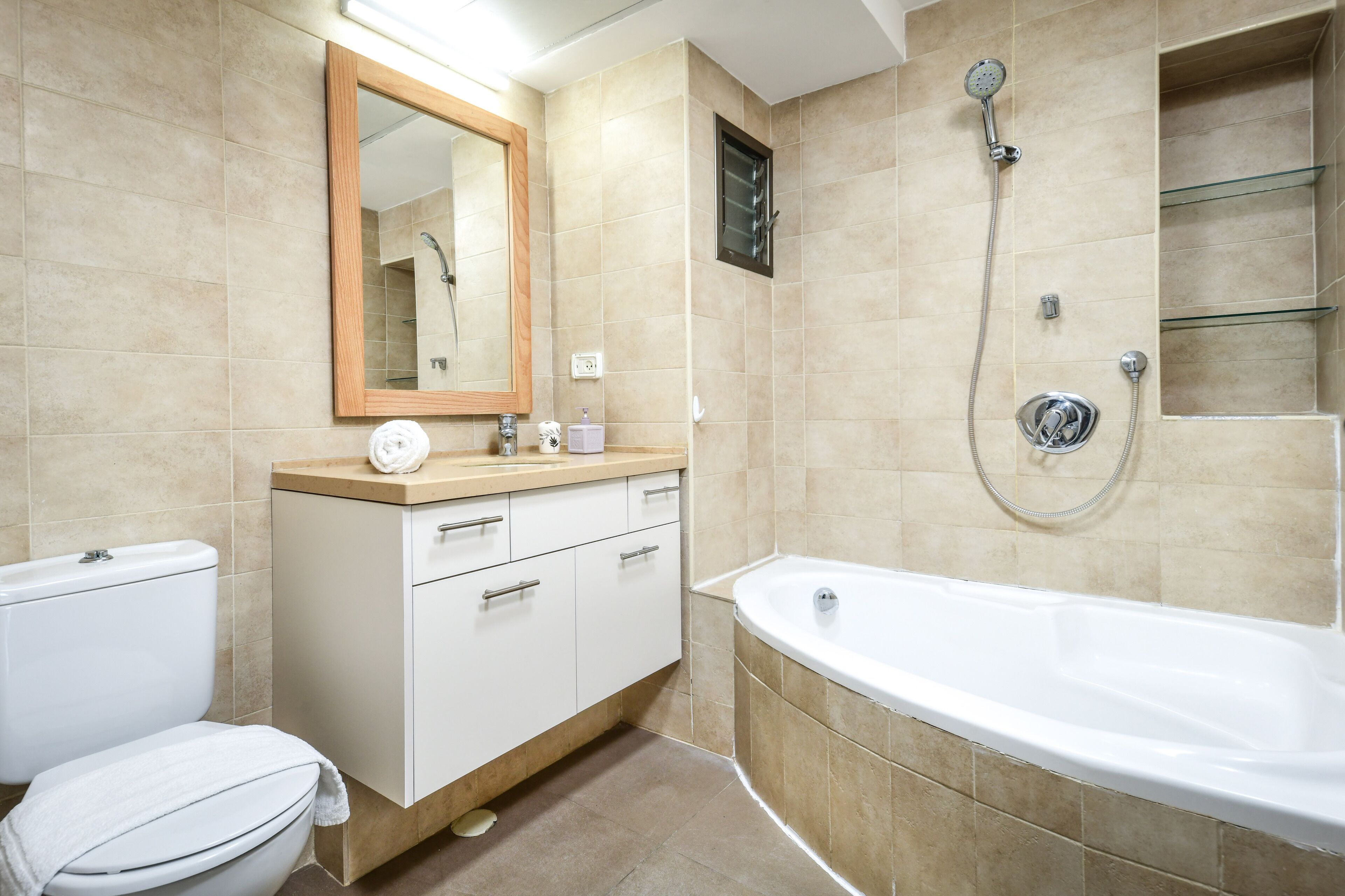 A modern bathroom with a toilet, sink, vanity, and bathtub.