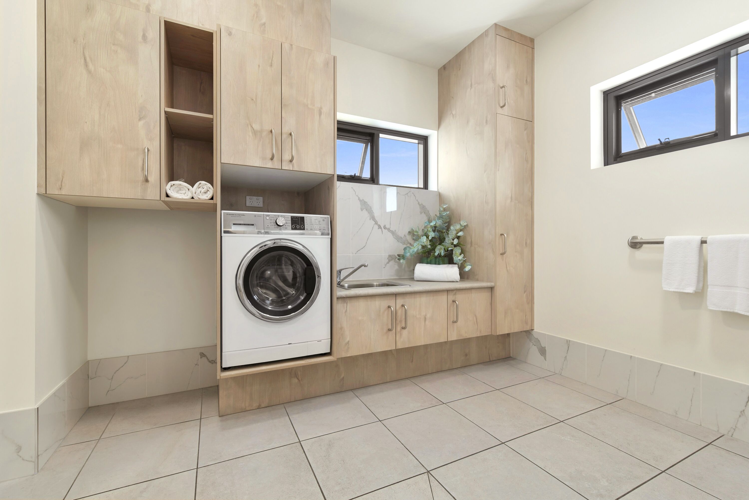 A compact kitchen with a built-in washer, a sink, and wooden cabinetry.