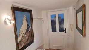 Un pasillo con una puerta blanca, un cuadro enmarcado y un teléfono en la pared.