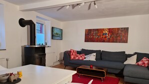 Una sala de estar con un sofá, una mesa, un tapete rojo, una chimenea y un cuadro en la pared.