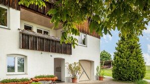 Ein zweistöckiges Gebäude mit Balkon, Blumentöpfen und Holzzaun.