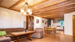 Ein geräumiger Wohnbereich mit Holzboden, einem Esstisch mit Stühlen, einer Couch und einem Schrank.