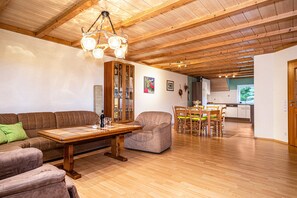 Un vaste espace de vie doté d’un plafond en bois, d’une table à manger avec des chaises, d’un canapé et d’un meuble.