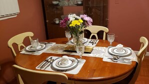 A dining table set for four with a vase of flowers, plates, cutlery, and glasses.