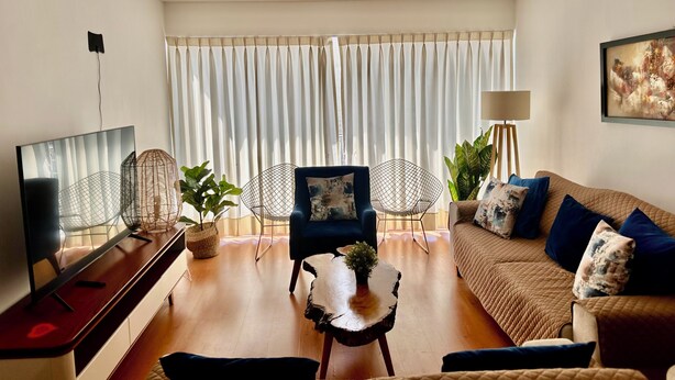 Ein Wohnzimmer mit einer Couch, einem Fernseher, einem Couchtisch und einem Sessel.