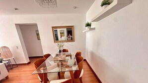 Ein moderner Essbereich mit einem Glastisch, Holzstühlen und einem Spiegel an der Wand.