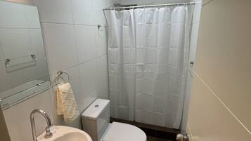 A small bathroom with a sink, toilet, and shower curtain.