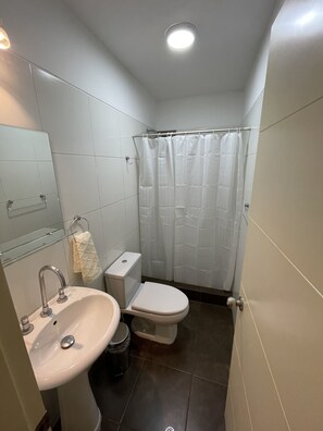 Ein kleines Badezimmer mit Waschbecken, Toilette und Duschvorhang.