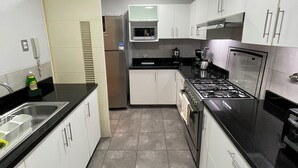 Eine moderne Küche mit weißen Schränken, einem Edelstahl-Kühlschrank, einer Mikrowelle, einem Herd und einem Spülbecken.