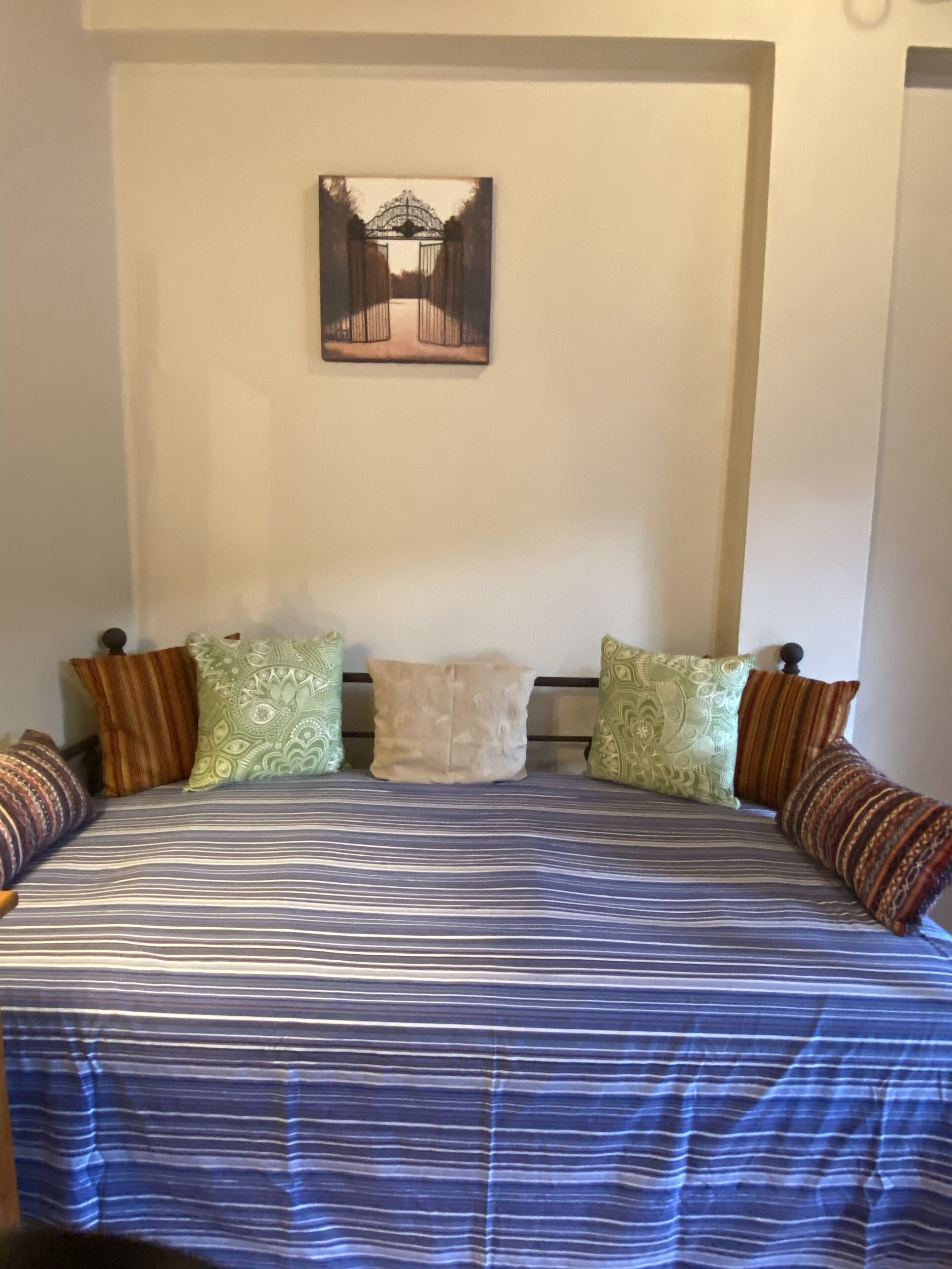 Un lit avec une couvre-lit à rayures, une tête de lit et plusieurs oreillers.