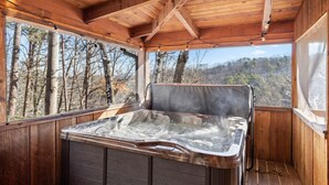 Una cabaña de madera con jacuzzi y ventanas amplias que dan a un bosque.