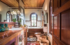 Een badkamer met een houten wastafel, een wastafel, een toilet en een douche.