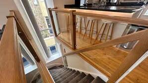 Eine Holztreppe mit Glastrennwand führt zu einem Küchenbereich.