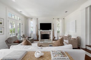 Relax in a cozy living space with a large TV above the fireplace, comfortable seating, and artwork on the walls.